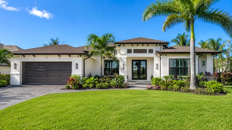 Modern Southwest Florida home with tropical landscaping under a bright blue sky